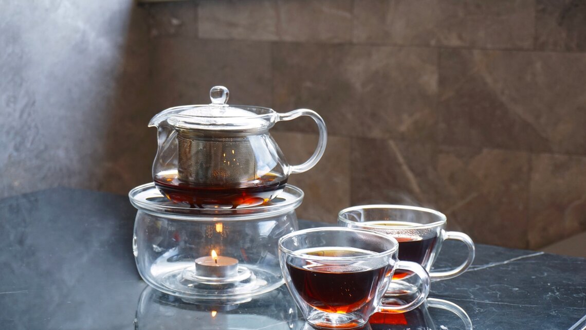玻璃茶杯和带保温器的玻璃茶壶 Tea glasses with glass teapot on warmer